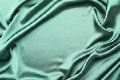 Crumpled green silk fabric as background, top view