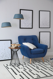 Beautiful artworks and comfortable armchair in stylish room. Interior design