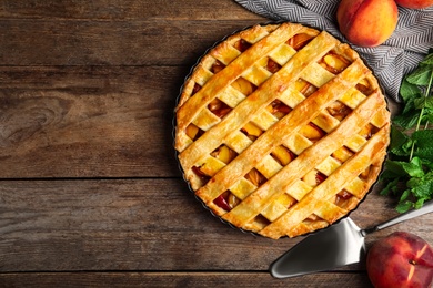 Photo of Delicious peach pie and fresh fruits on wooden table, flat lay. Space for text