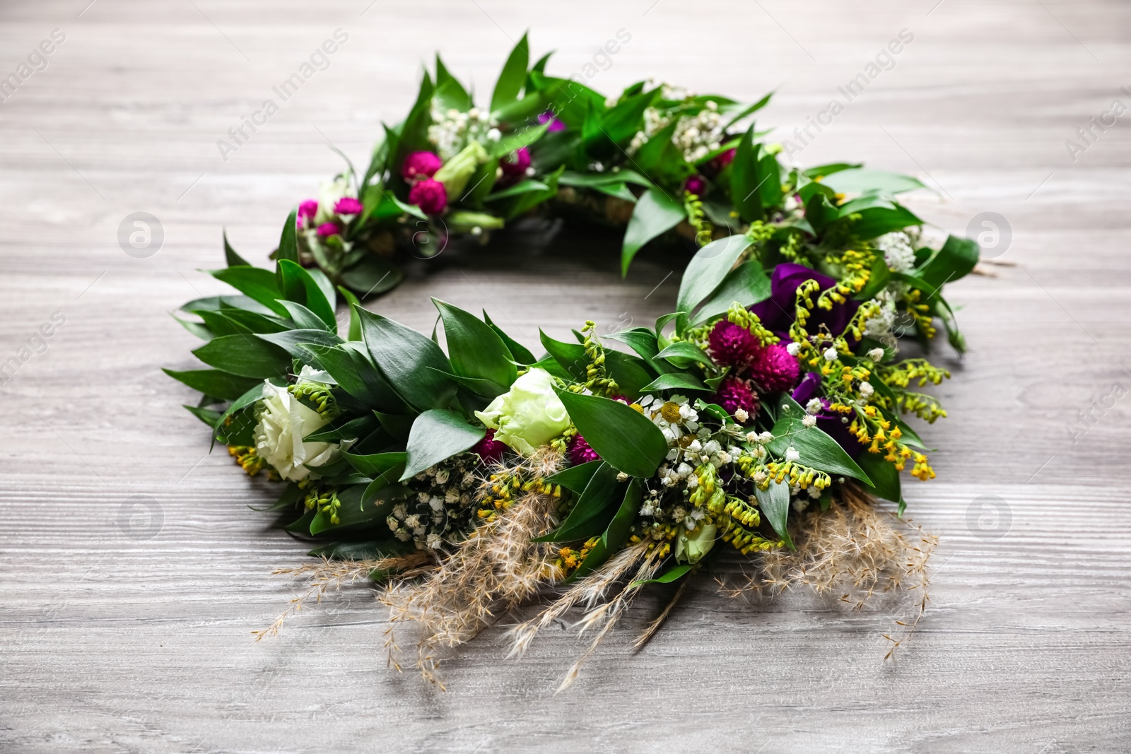 Photo of Beautiful wreath made of flowers and leaves on wooden table