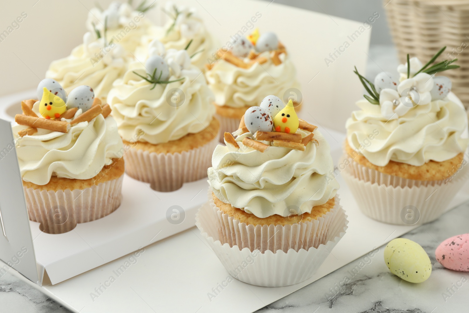 Photo of Tasty Easter cupcakes with vanilla cream on white marble table