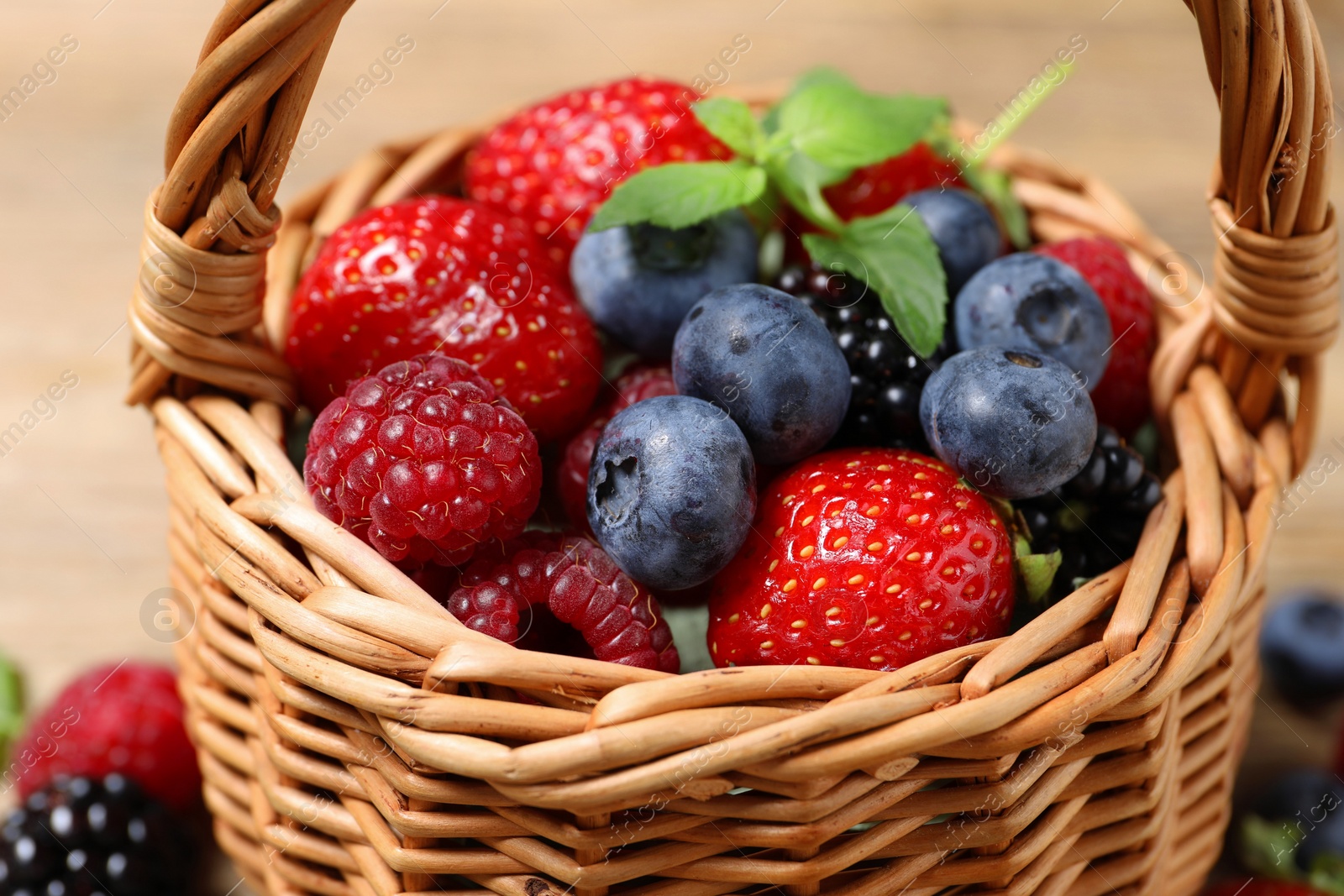 Many different fresh ripe berries in wicker basket, closeup Photo of Many different fresh ripe berries in wicker basket, closeup