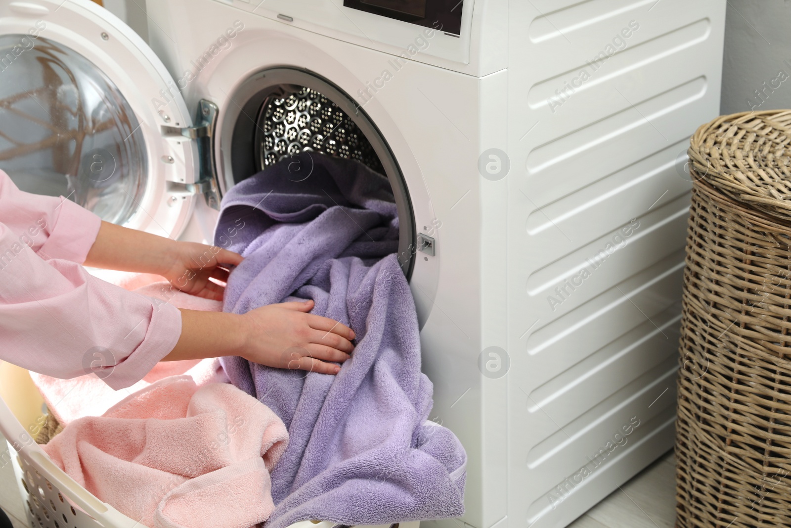 Photo of Woman taking towels out of washing machine in laundry room