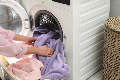Photo of Woman taking towels out of washing machine in laundry room