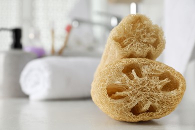 Natural loofah sponges on table in bathroom, closeup. Space for text
