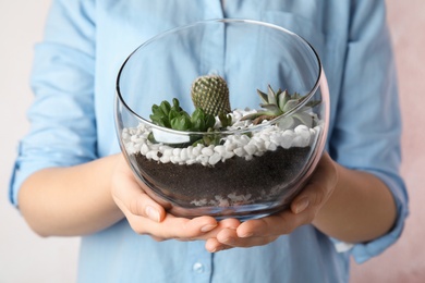 Photo of Young woman holding florarium with different succulents on color background, closeup