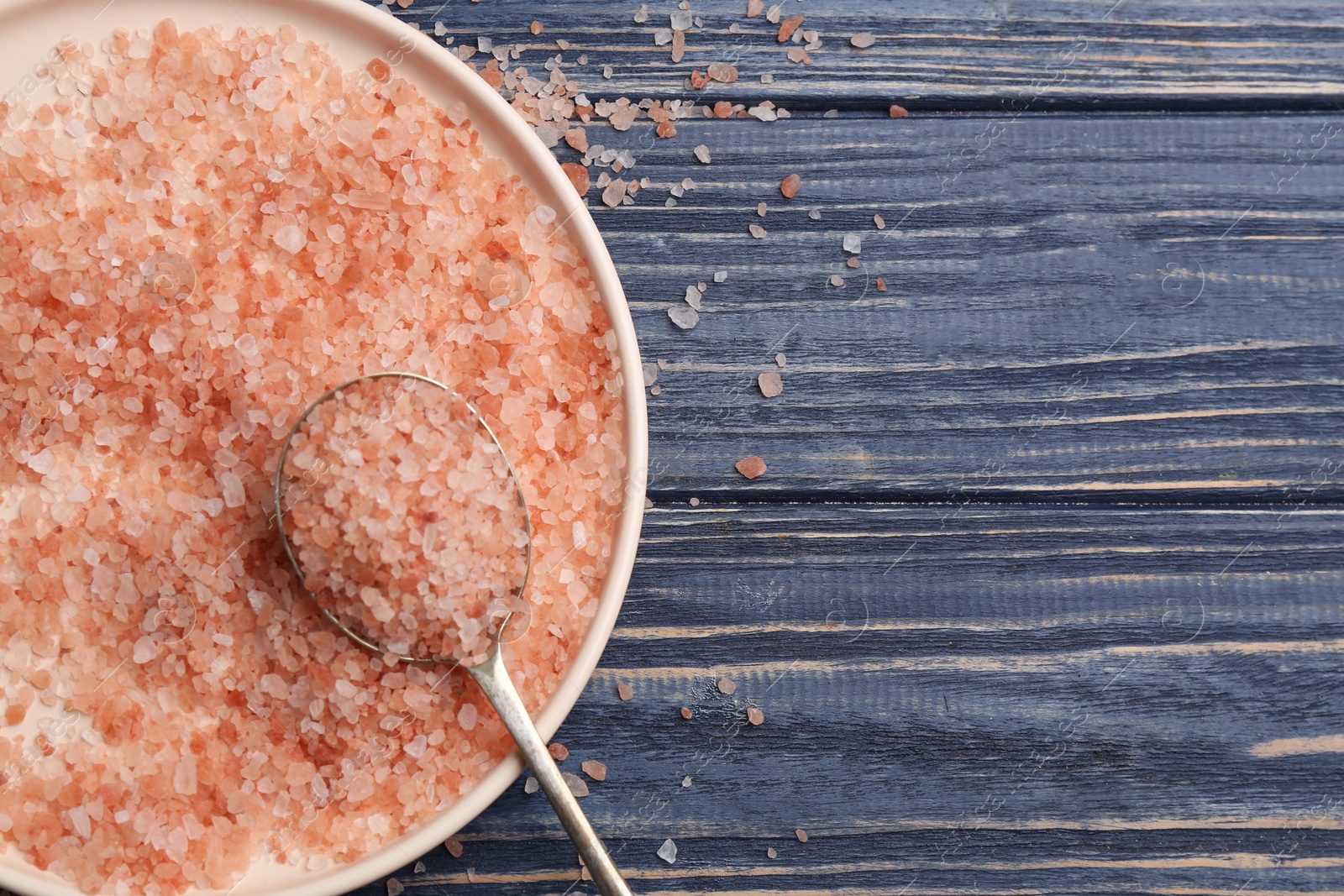 Photo of Pink himalayan salt on blue wooden table, flat lay. Space for text