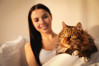 Photo of Beautiful young woman with her cute cat on bed, focus on pet