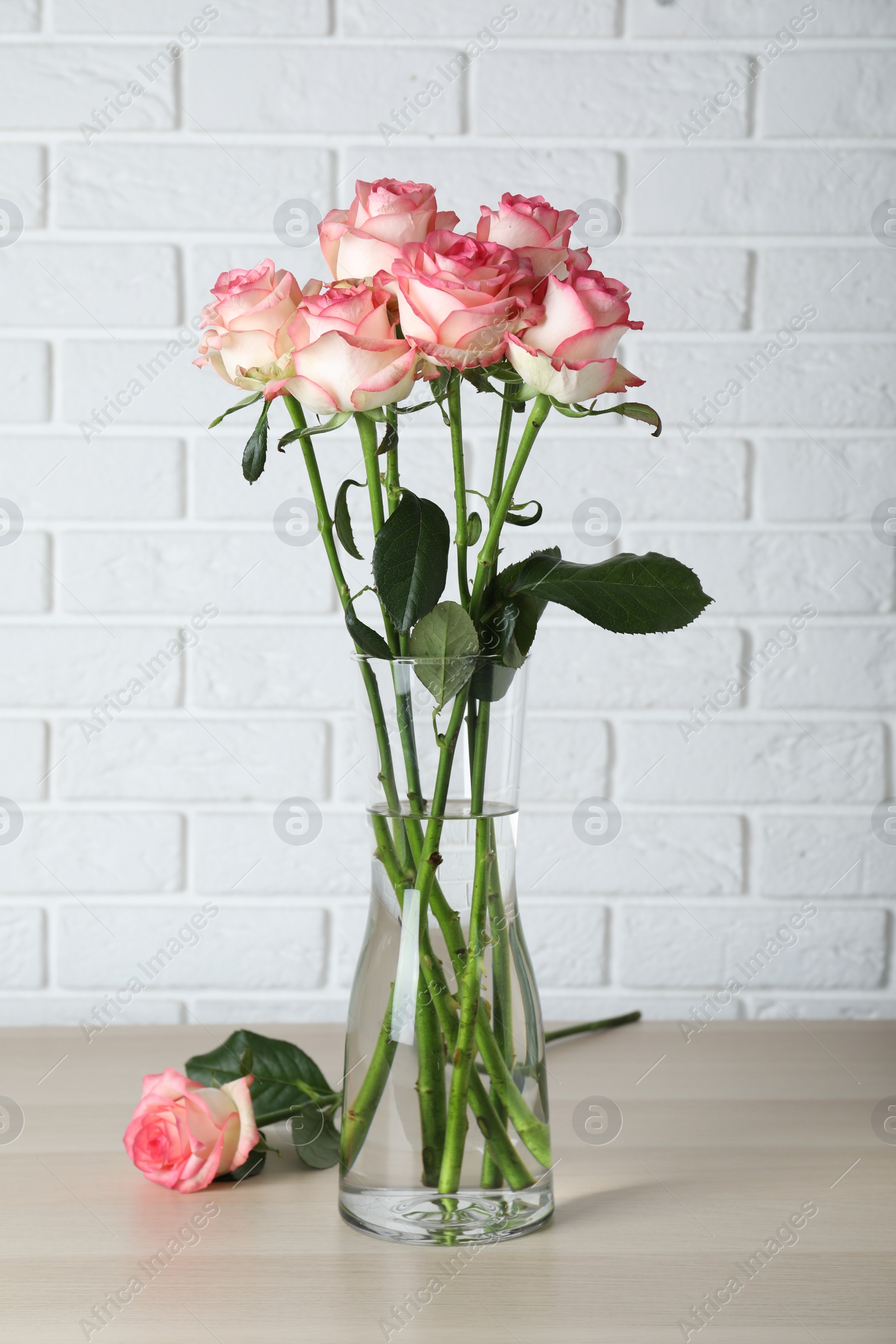 Photo of Vase with beautiful pink roses on wooden table