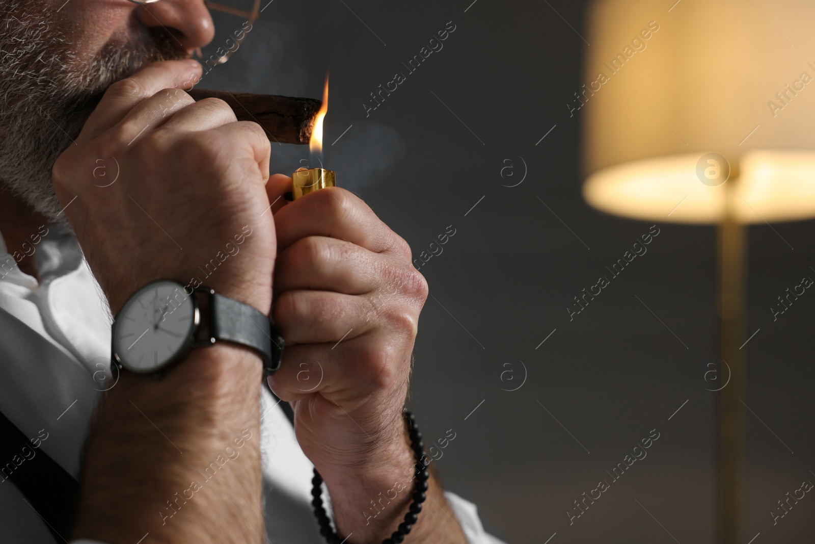 Photo of Bearded man lighting cigar indoors, closeup. Space for text