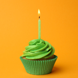 Photo of Delicious birthday cupcake with green cream and burning candle on yellow background