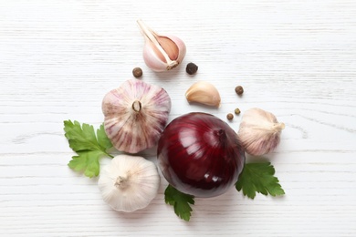Photo of Composition with garlic, parsley and onion on white wooden background, top view