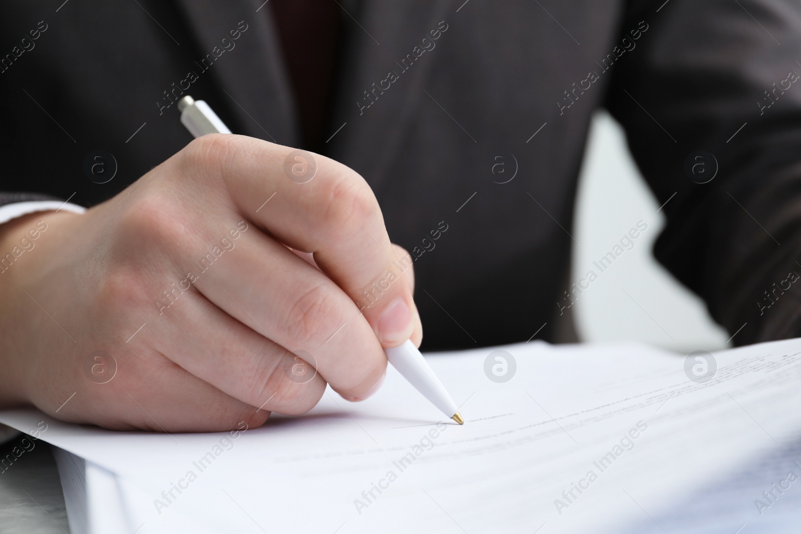 Photo of Man signing document at table in office, closeup