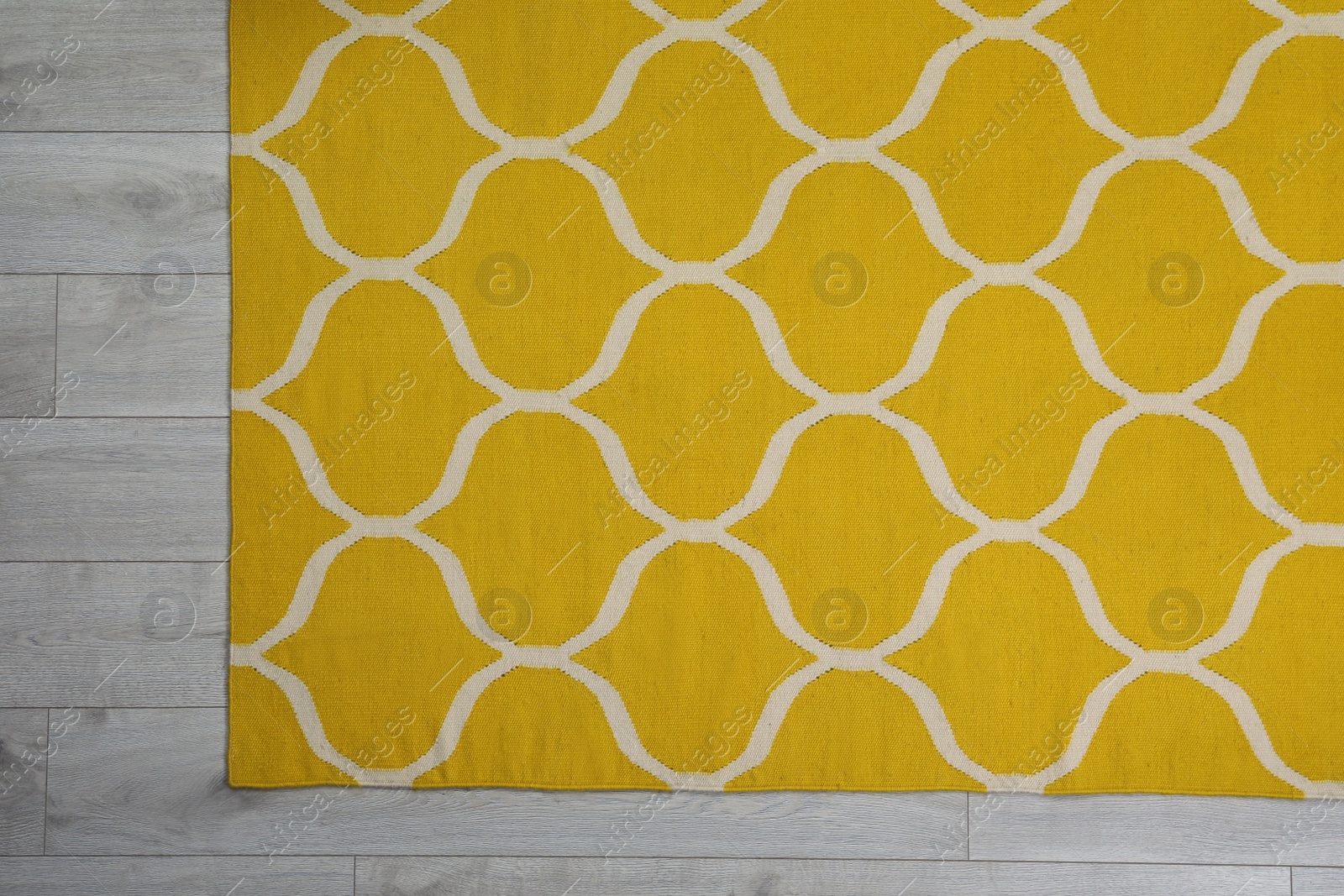 Photo of Yellow carpet with geometric pattern on wooden floor, top view