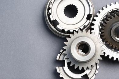 Photo of Different stainless steel gears on grey background, flat lay. Space for text