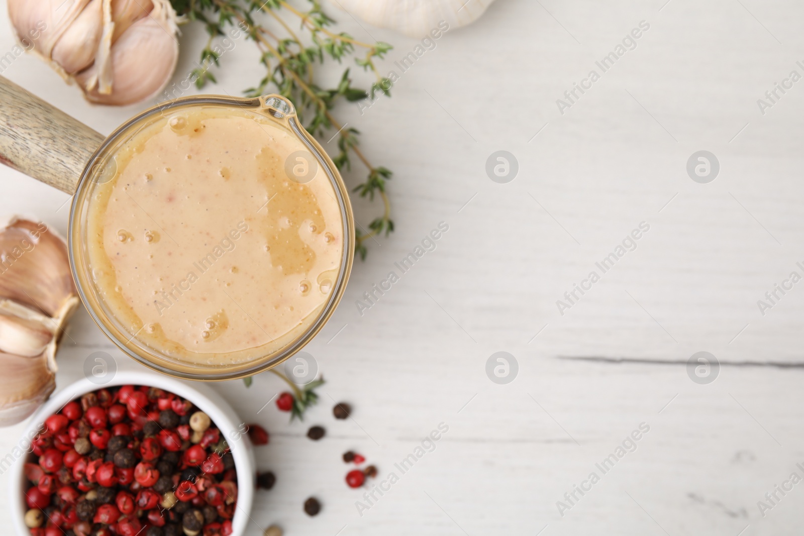 Photo of Delicious turkey gravy, garlic, thyme and peppercorns on white wooden table, flat lay. Space for text
