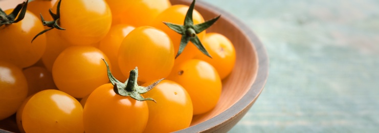 Photo of Ripe yellow tomatoes on light blue wooden table, closeup. Space for text