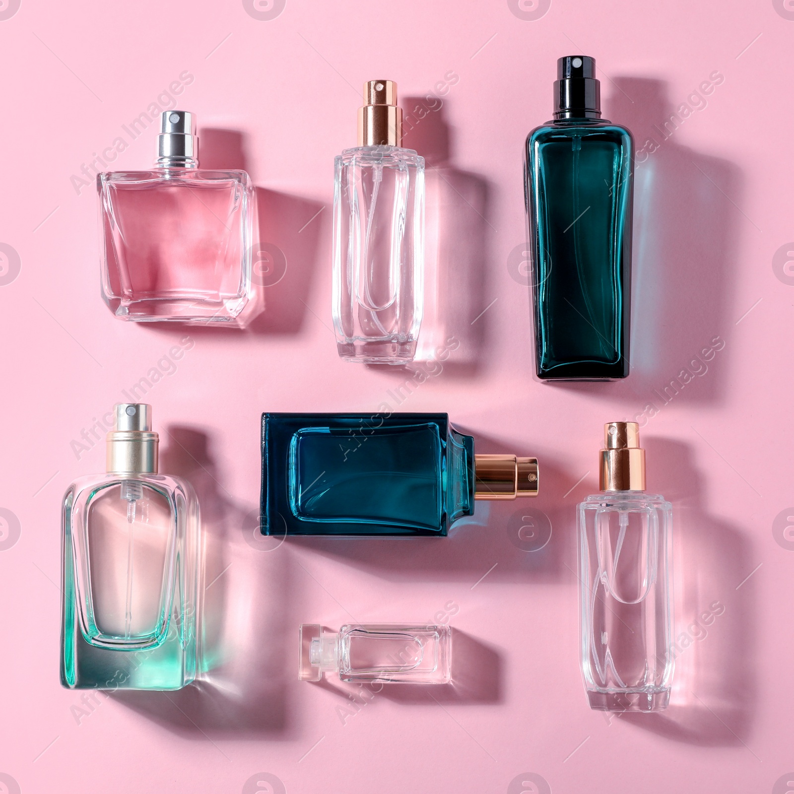 Photo of Bottles of perfume on color background, top view