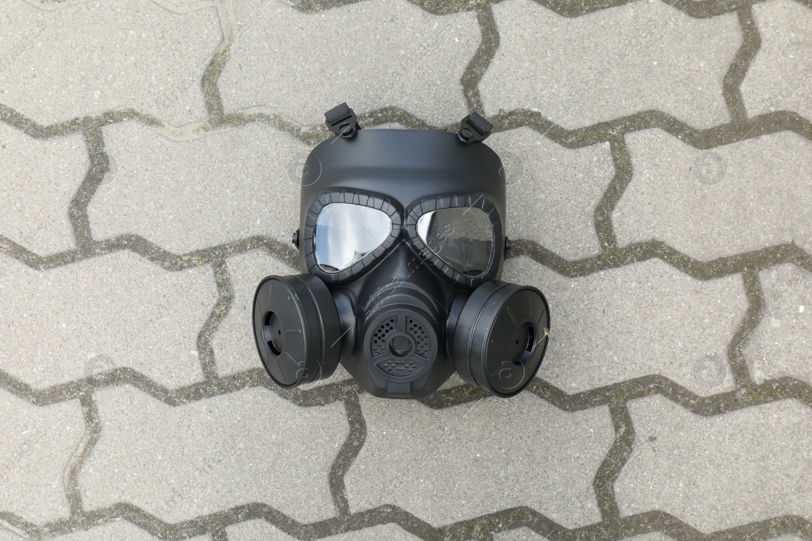 Photo of One gas mask on paved pathway outdoors, top view