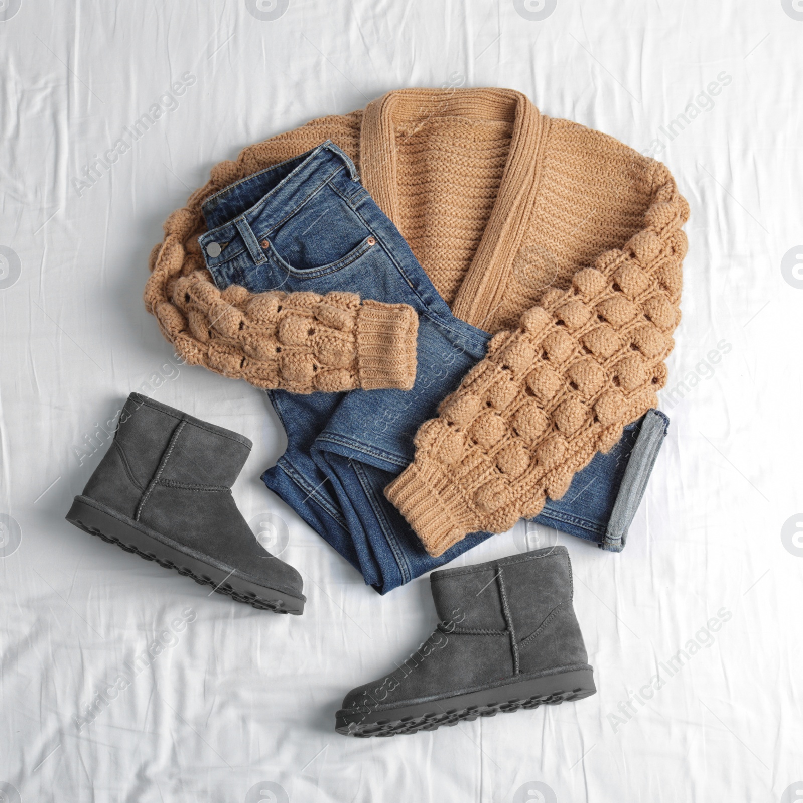 Photo of Flat lay composition with jeans, sweater and shoes on white fabric