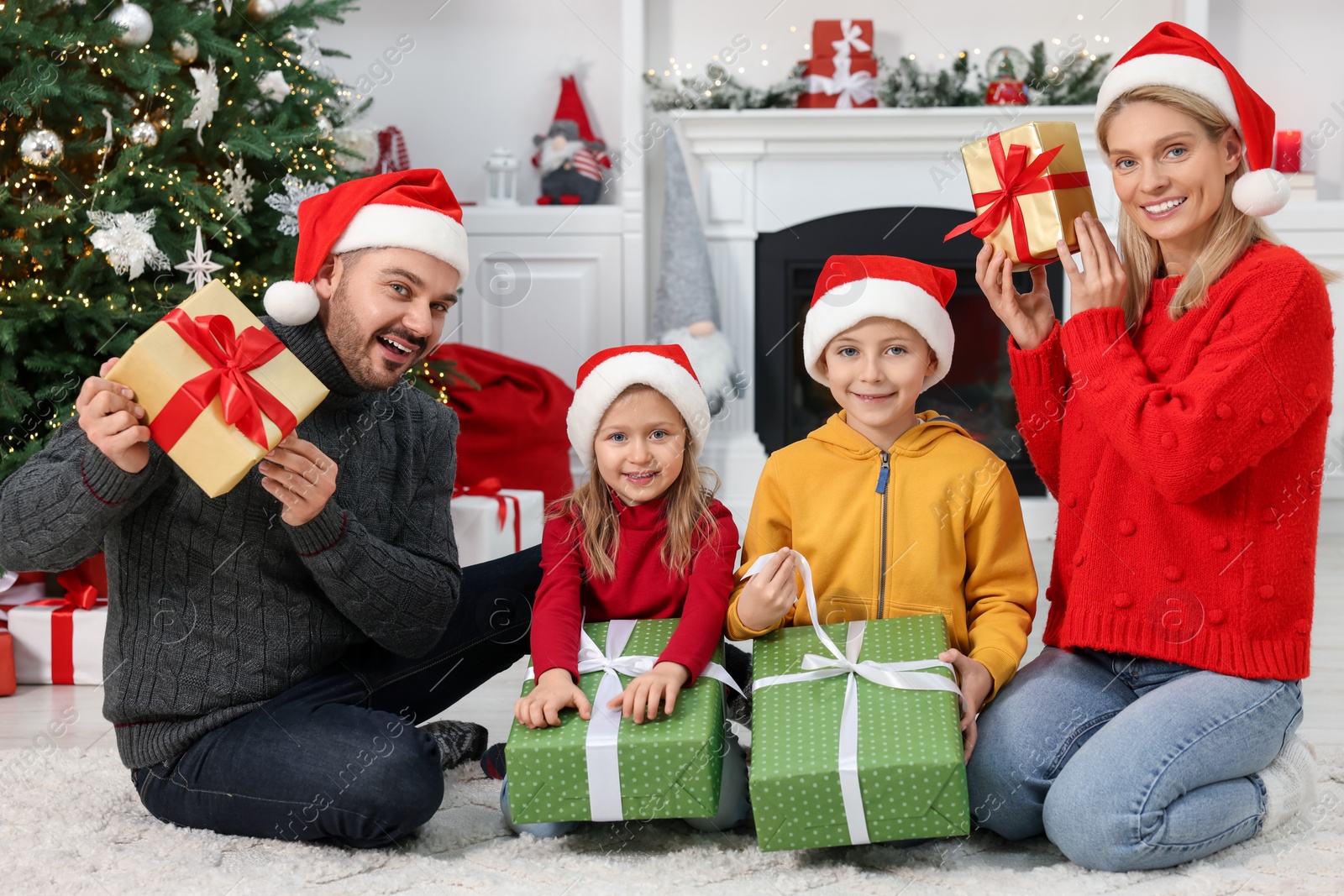 Photo of Happy family in Santa hats with Christmas gifts at home