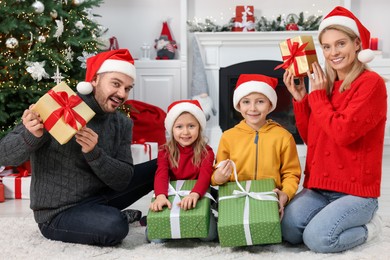 Happy family in Santa hats with Christmas gifts at home