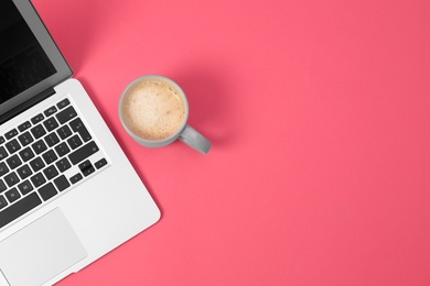 Photo of Modern laptop and cup of coffee on pink background, top view. Space for text