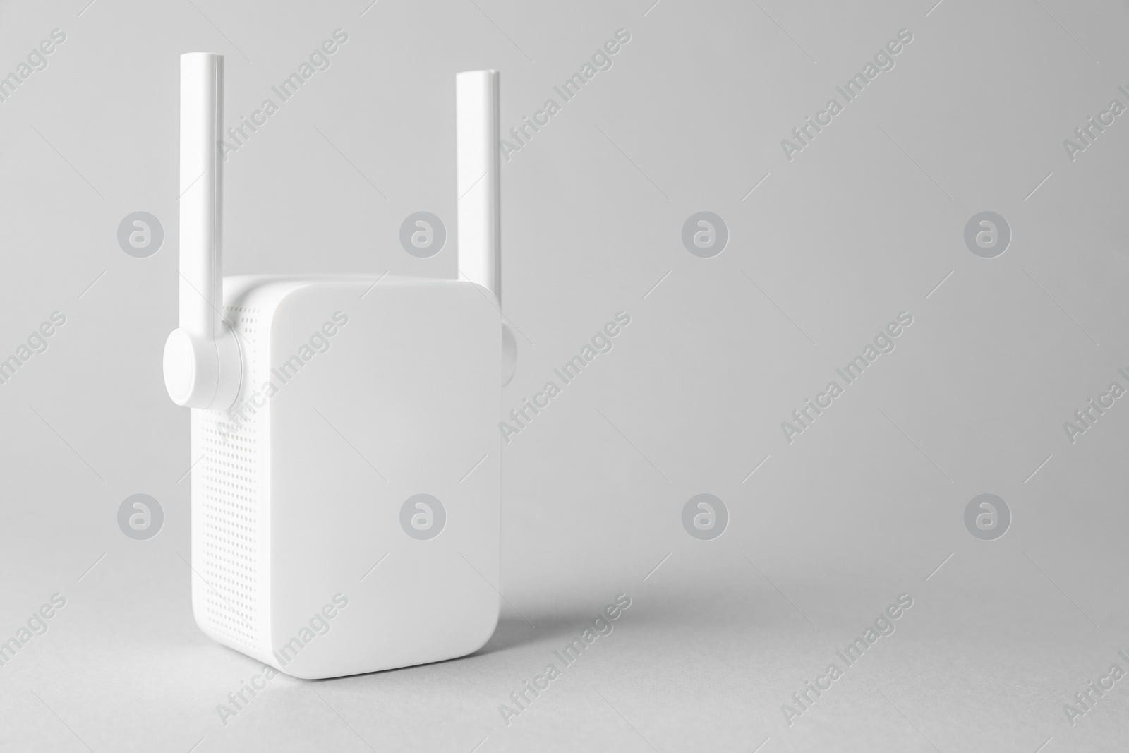 Photo of New modern Wi-Fi repeater on light gray background, space for text