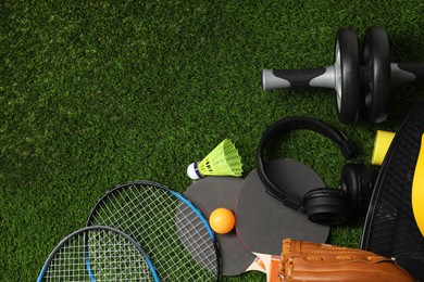 Photo of Different sports equipment on green grass, above view. Space for text