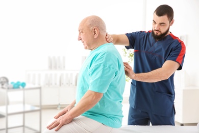 Young physiotherapist working with senior patient in clinic