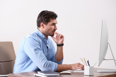 Handsome young man working with computer at table in office