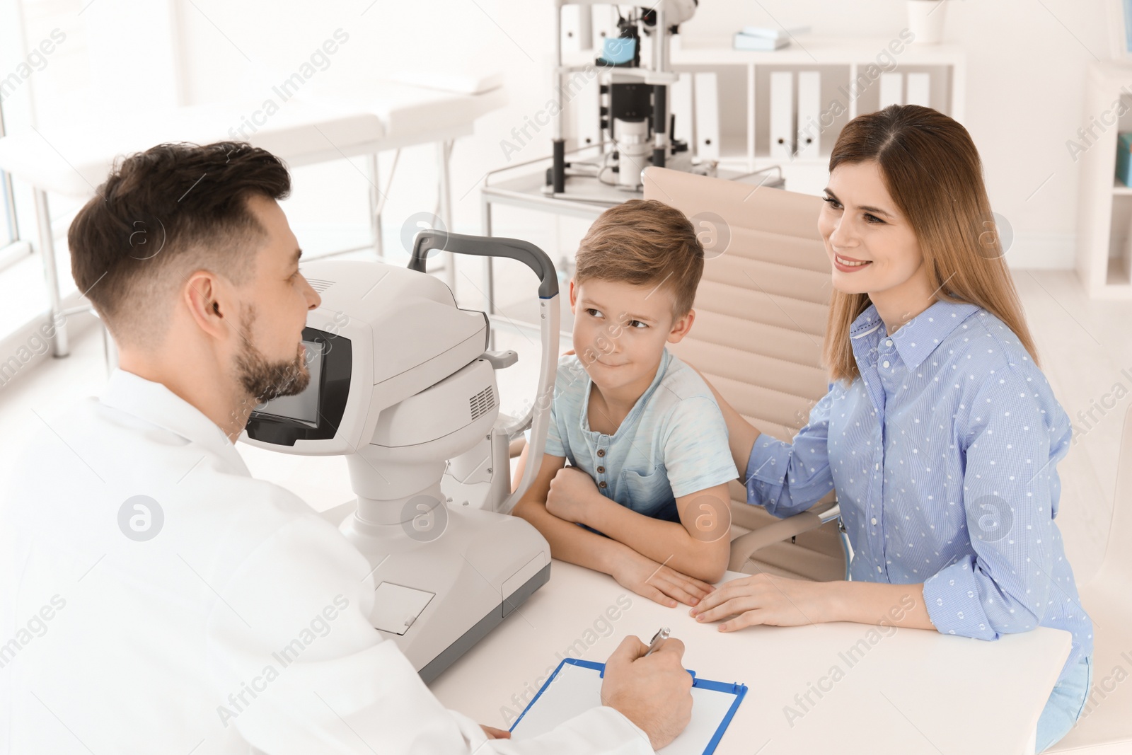 Photo of Little boy with mother visiting ophthalmologist in clinic