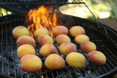 Photo of Modern grill with tasty juicy peaches outdoors, closeup
