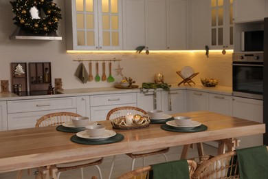 Photo of Table with dishware in beautiful kitchen decorated for Christmas. Interior design