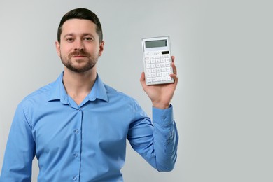 Photo of Accountant showing calculator on light grey background. Space for text