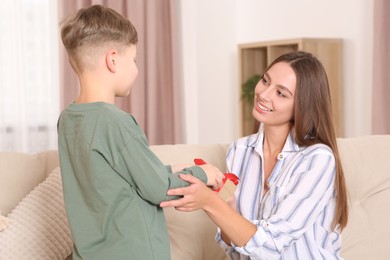 Photo of Little boy presenting gift to his mother at home