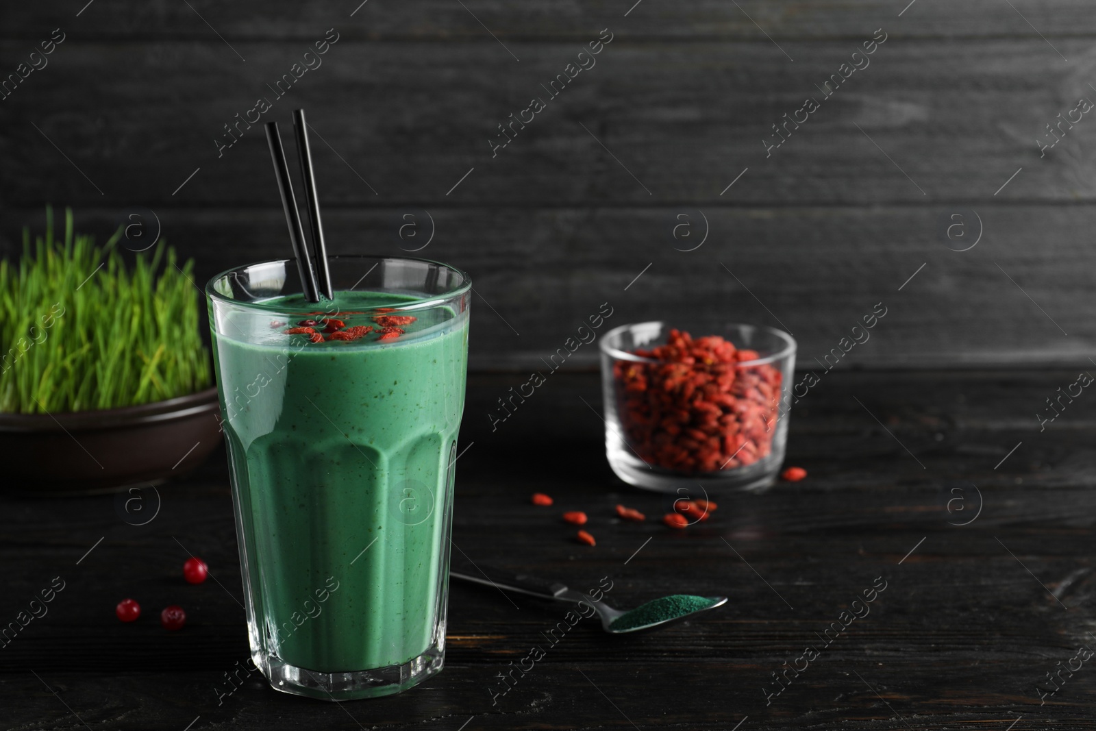 Photo of Glass of spirulina smoothie with goji berries on table. Space for text