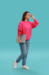 Young woman with modern laptop on light blue background