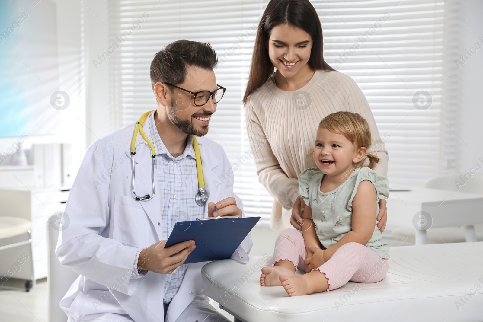 Photo of Mother and her cute baby having appointment with pediatrician in clinic. Doctor examining little girl