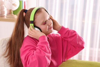 Photo of Cute indie girl in headphones listening music at home