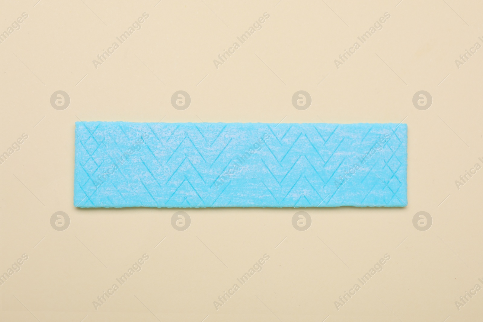 Photo of Stick of tasty chewing gum on beige background, top view