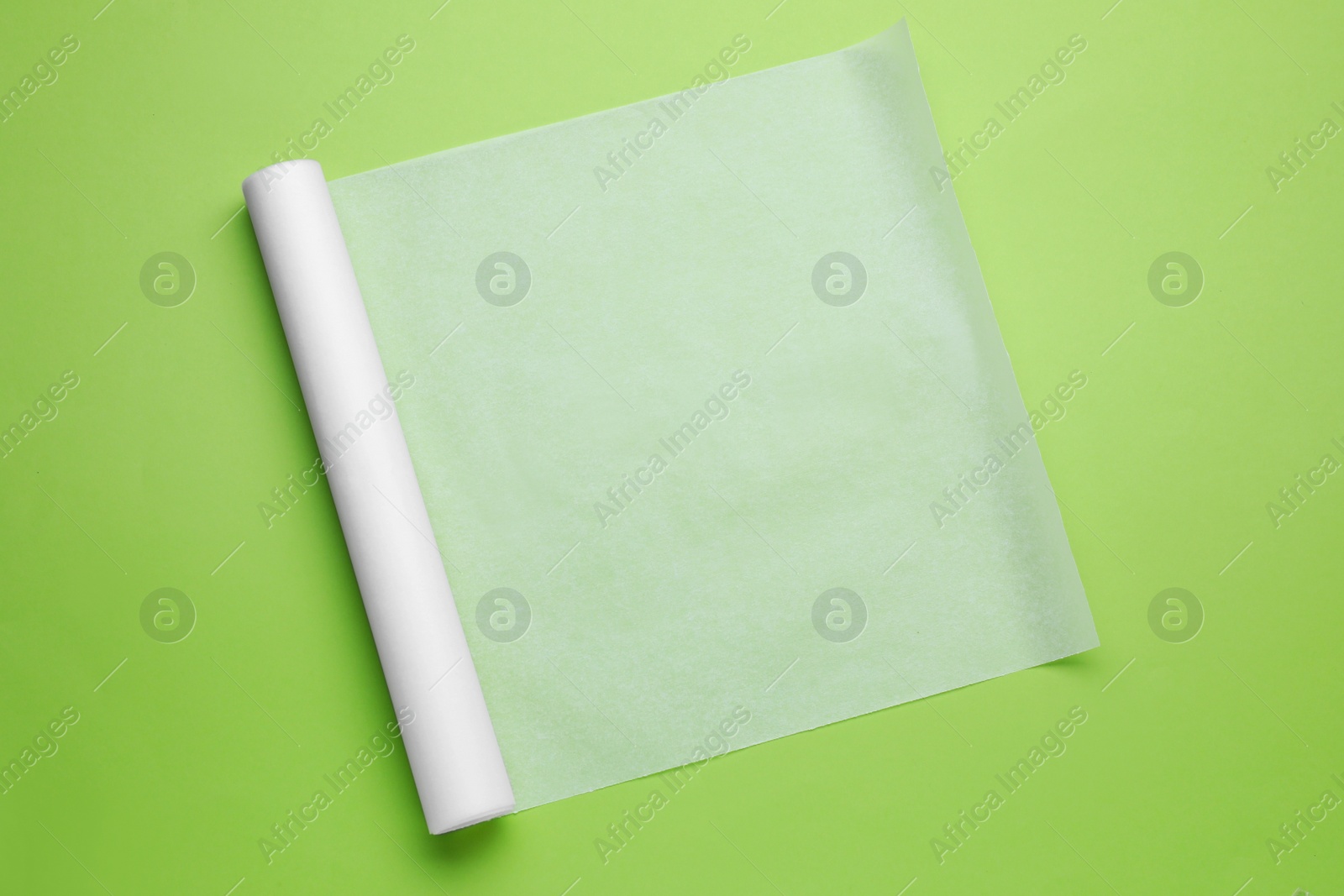 Photo of Roll of baking paper on light green background, top view