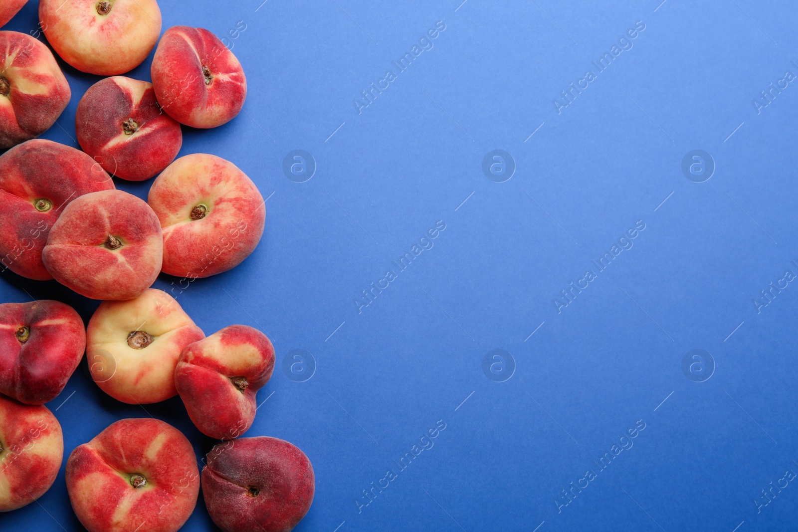 Photo of Fresh donut peaches on blue background, flat lay. Space for text