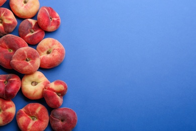 Photo of Fresh donut peaches on blue background, flat lay. Space for text