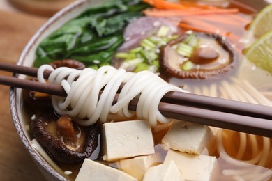 Bowl of vegetarian ramen and chopsticks on table, closeup