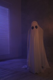 Creepy ghost. Woman covered with sheet in color lights