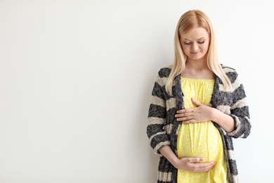 Portrait of beautiful pregnant woman on light background. Space for text