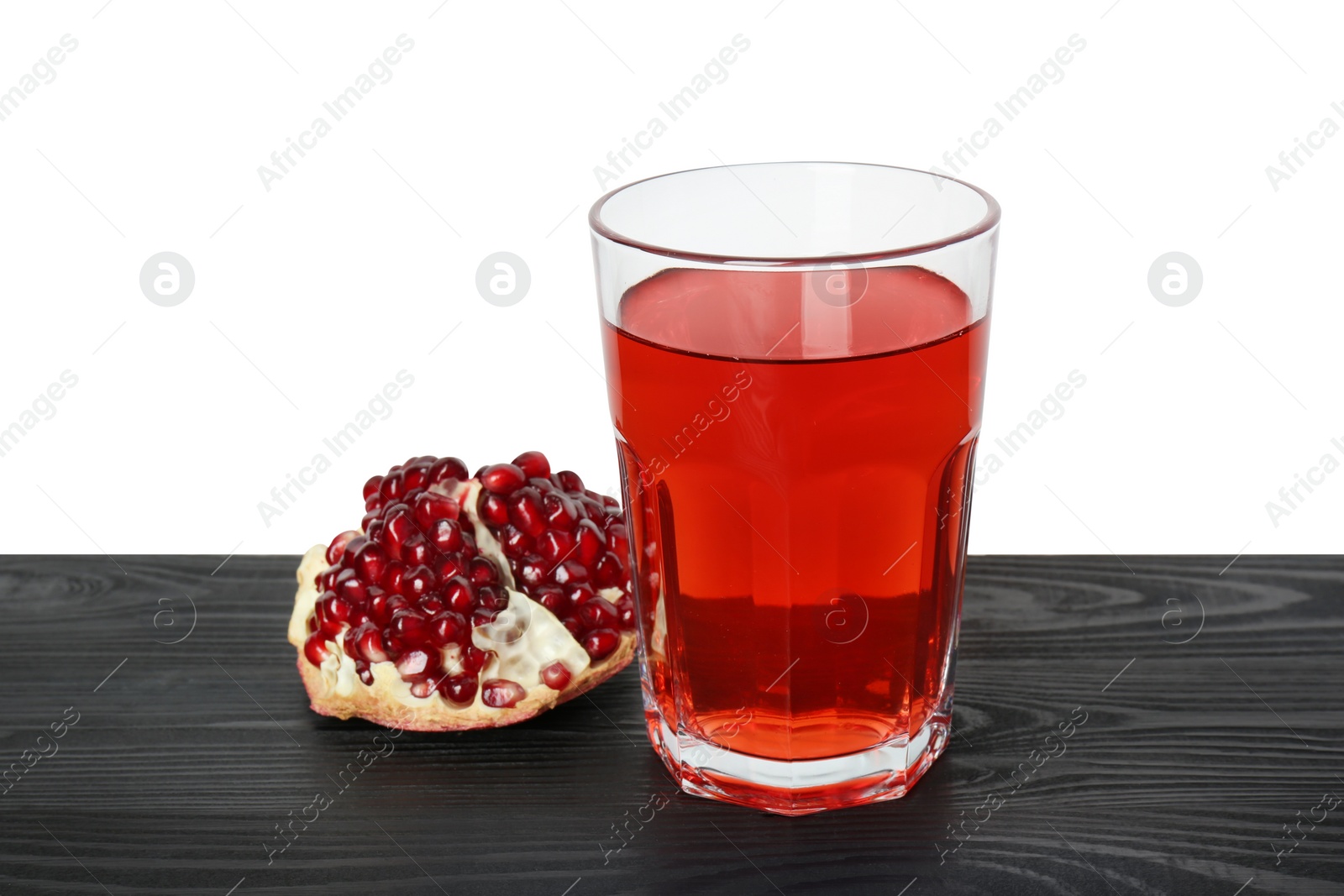 Photo of Refreshing pomegranate juice in glass and fruit on black wooden table against white background