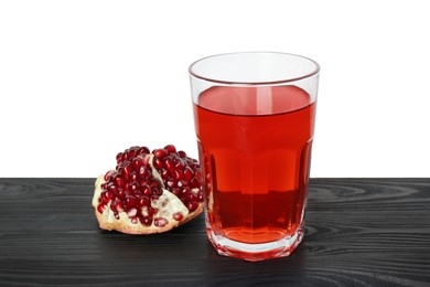 Photo of Refreshing pomegranate juice in glass and fruit on black wooden table against white background