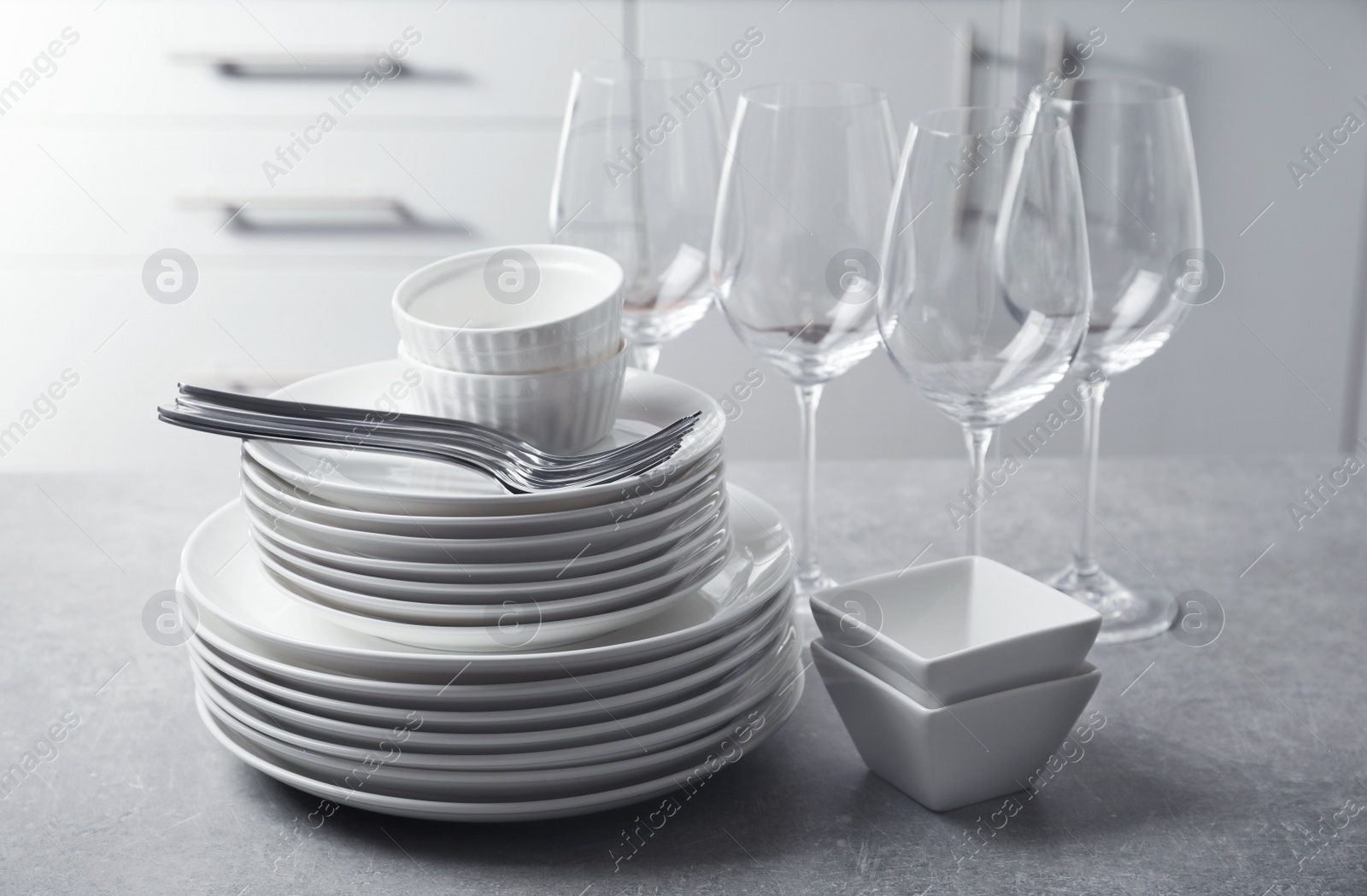 Photo of Set of clean dishes and cutlery on table in kitchen